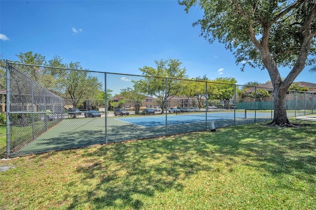 view of sport court with a lawn and fence