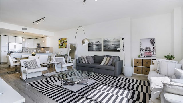 living area featuring rail lighting, wood finished floors, and visible vents