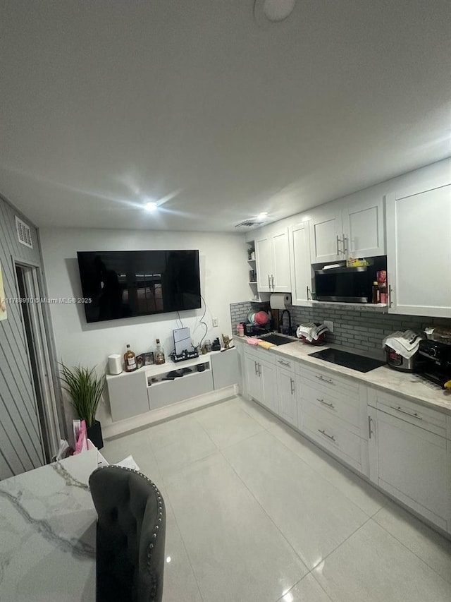 11245 SW 47th Ter, Miami, FL 33165 - kitchen featuring decorative backsplash, light tile patterned floors, black electric stovetop, stainless steel microwave, and white cabinetry