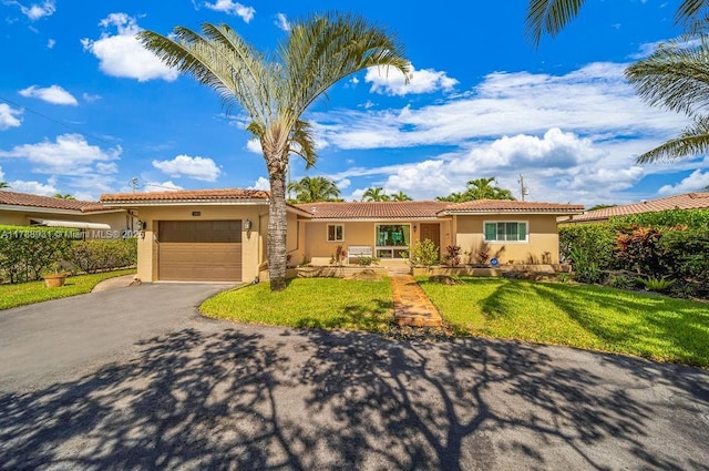 single story home with aphalt driveway, a tile roof, an attached garage, stucco siding, and a front lawn