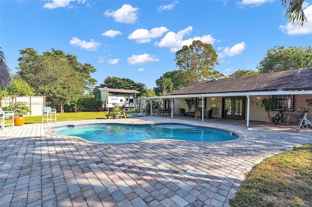 outdoor pool with a yard, french doors, and a patio area