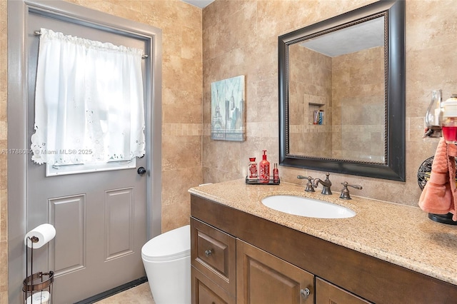 bathroom featuring tile walls, vanity, and toilet