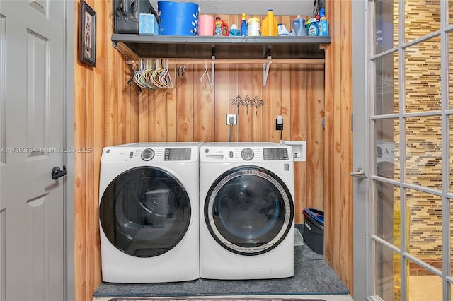laundry room with wooden walls, washer and clothes dryer, and laundry area