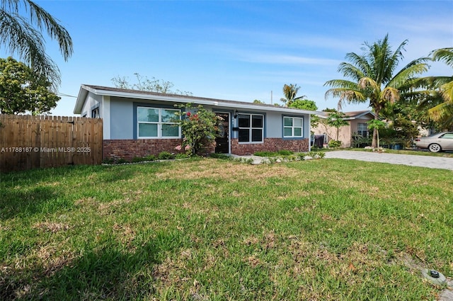 ranch-style house featuring fence, stucco siding, driveway, brick siding, and a front yard