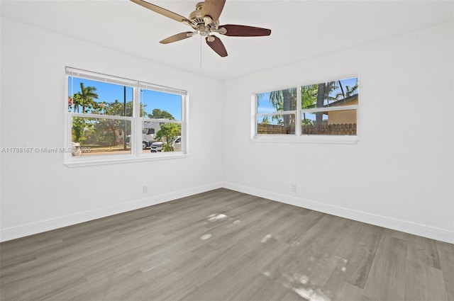 spare room featuring wood finished floors, baseboards, and a ceiling fan