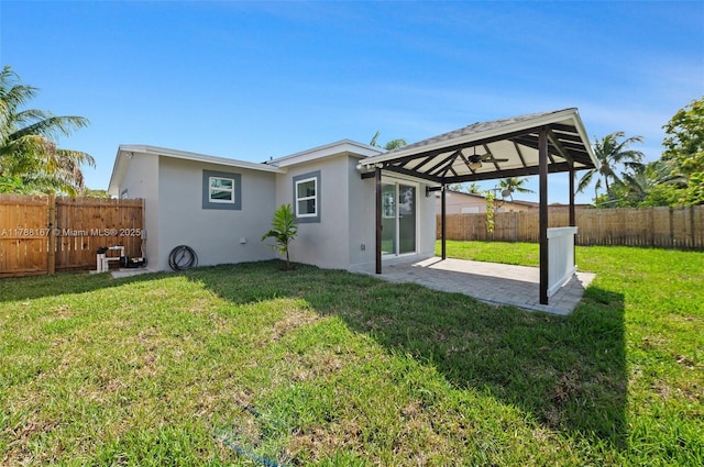 rear view of house featuring a yard, a patio area, a fenced backyard, and stucco siding