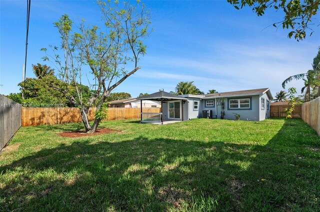 back of house with central air condition unit, a patio area, a yard, and a fenced backyard