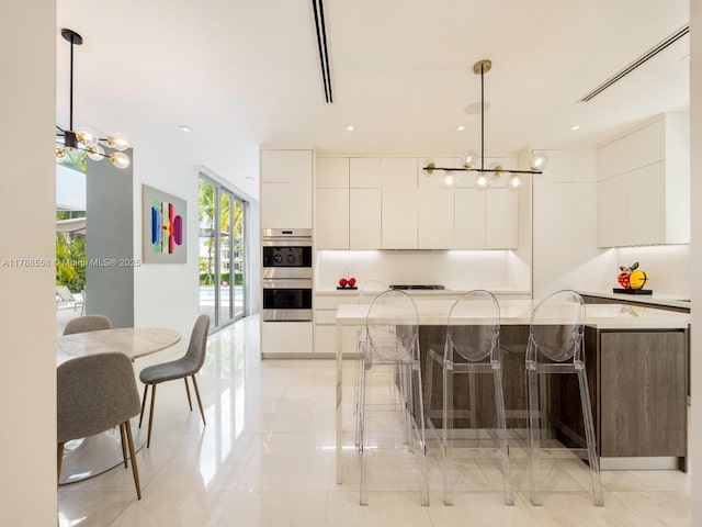 kitchen featuring an inviting chandelier, modern cabinets, and double oven
