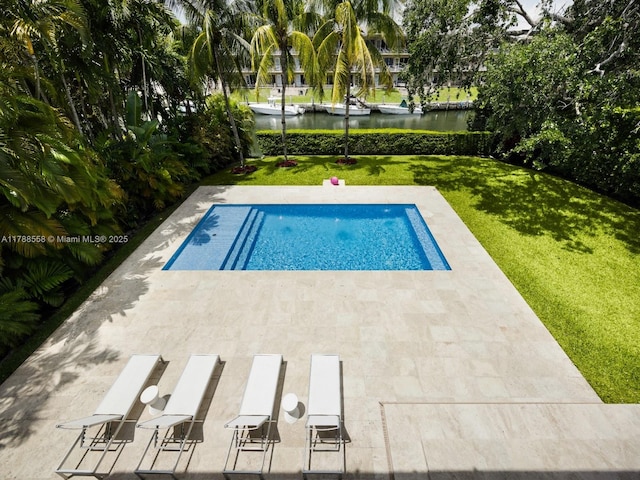 pool featuring a yard, a water view, and a patio area