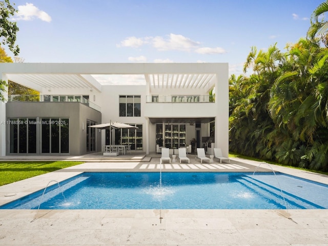 back of house featuring a patio, an outdoor pool, stucco siding, and a balcony