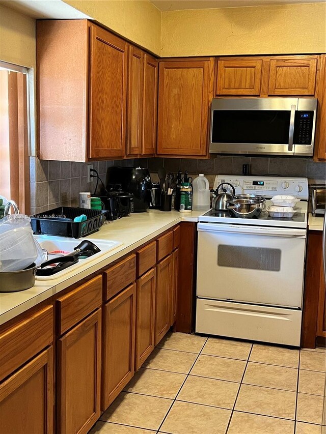 3530 NW 194th Ter, Miami Gardens, FL 33056 - kitchen with stainless steel microwave, light countertops, electric stove, and brown cabinets