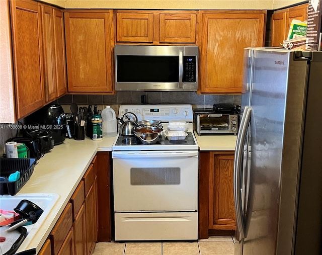 3530 NW 194th Ter, Miami Gardens, FL 33056 - kitchen featuring light tile patterned floors, light countertops, brown cabinets, and appliances with stainless steel finishes