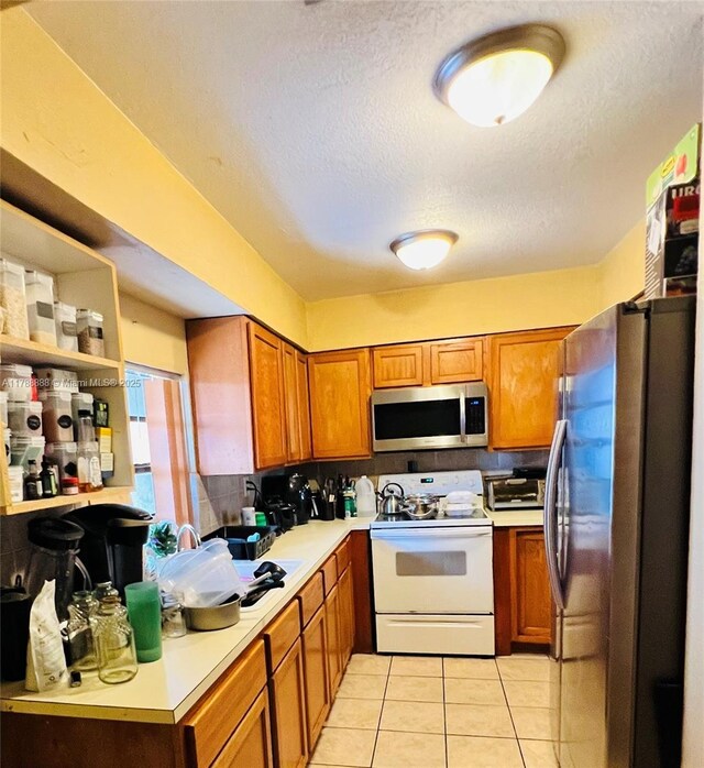 3530 NW 194th Ter, Miami Gardens, FL 33056 - kitchen with stainless steel appliances, light countertops, a textured ceiling, and brown cabinets