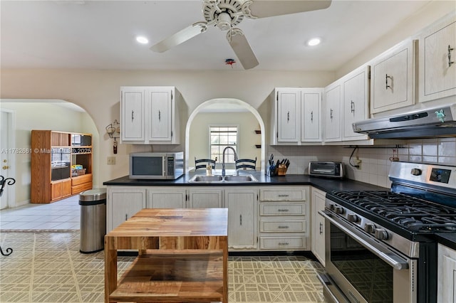 11421 NW 37th Pl, Sunrise, FL 33323 - kitchen featuring appliances with stainless steel finishes, a sink, extractor fan, arched walkways, and dark countertops