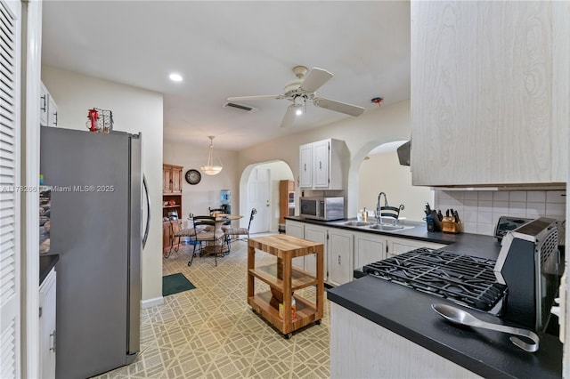 11421 NW 37th Pl, Sunrise, FL 33323 - kitchen featuring appliances with stainless steel finishes, a sink, dark countertops, arched walkways, and a ceiling fan