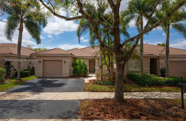 view of front of house featuring a tile roof, stucco siding, an attached garage, and aphalt driveway