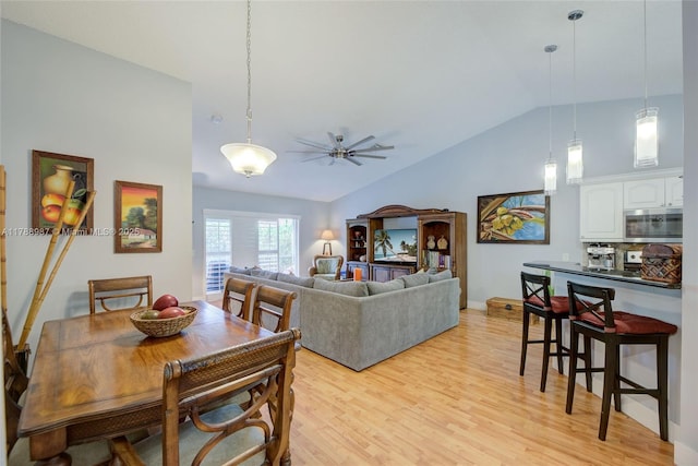 dining space with light wood finished floors, a ceiling fan, vaulted ceiling, and baseboards