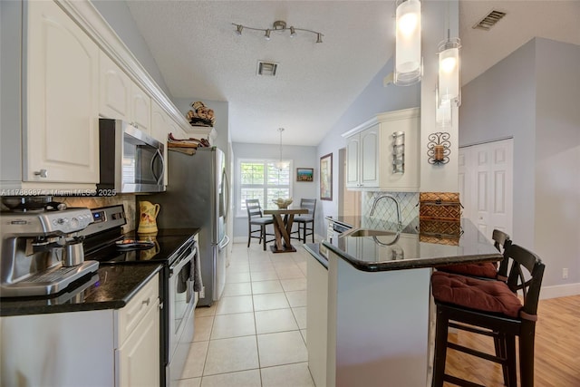 kitchen featuring appliances with stainless steel finishes, backsplash, a sink, visible vents, and a peninsula