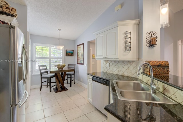 kitchen featuring decorative backsplash, appliances with stainless steel finishes, white cabinets, a sink, and lofted ceiling
