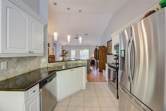 kitchen with a sink, stainless steel appliances, vaulted ceiling, decorative light fixtures, and a peninsula