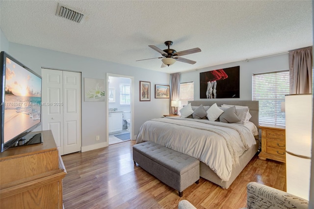 bedroom with a textured ceiling, visible vents, light wood-style floors, and multiple windows