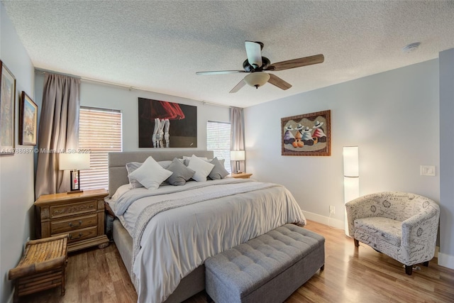 bedroom with a textured ceiling, ceiling fan, wood finished floors, and baseboards