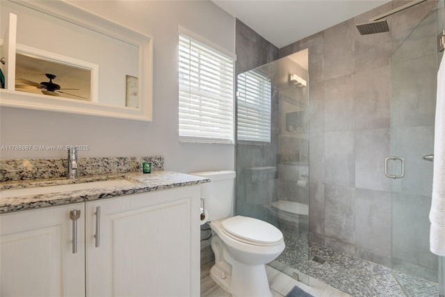 full bath featuring a shower stall, a ceiling fan, toilet, and vanity