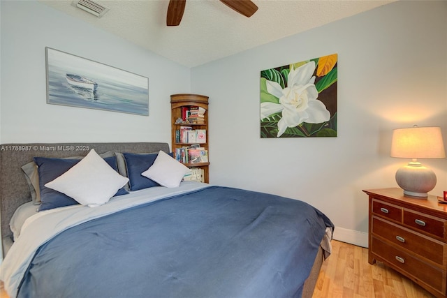 bedroom with a textured ceiling, visible vents, a ceiling fan, and light wood-type flooring