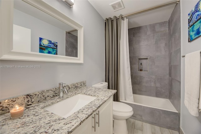 full bath featuring wood finished floors, visible vents, toilet, vanity, and shower / tub combo with curtain