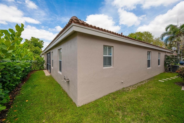 view of home's exterior with stucco siding, central AC unit, and a lawn
