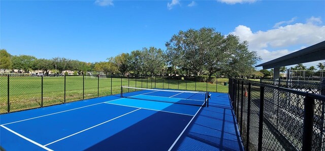 view of tennis court with fence, a yard, and community basketball court