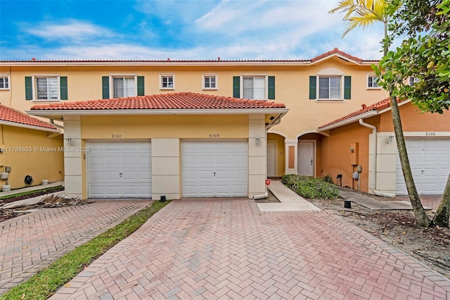 view of front of home with stucco siding, a tile roof, and driveway