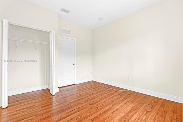 unfurnished bedroom featuring baseboards, a closet, visible vents, and light wood-type flooring
