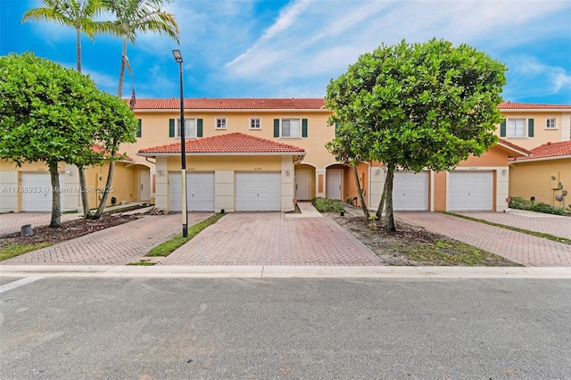 view of property with a tiled roof, driveway, and stucco siding