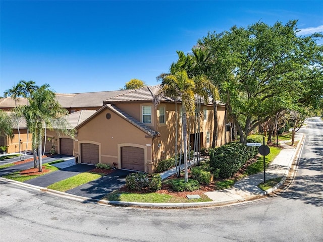 townhome / multi-family property featuring stucco siding, driveway, and a tiled roof
