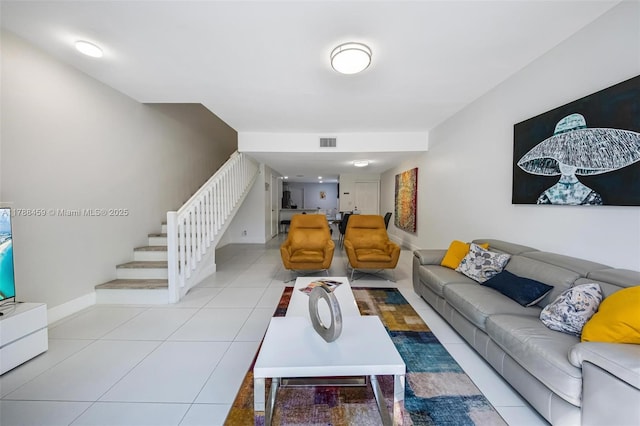 living room featuring stairway, visible vents, baseboards, and light tile patterned floors
