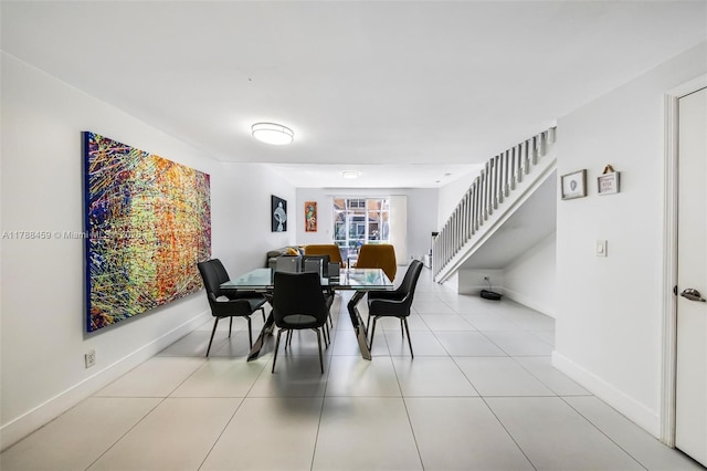 dining space with stairway, baseboards, and tile patterned floors