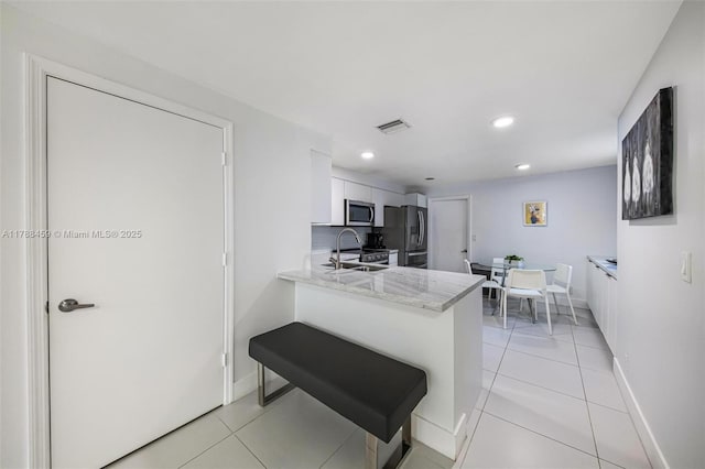 kitchen featuring stainless steel appliances, visible vents, a sink, light tile patterned floors, and baseboards