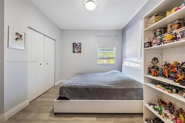 bedroom featuring wood finished floors, a closet, and baseboards
