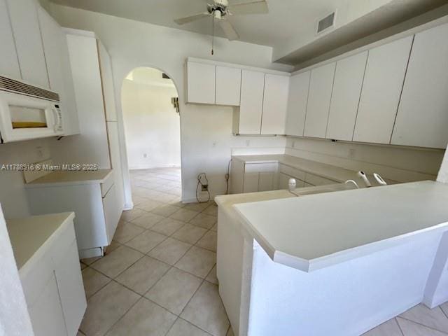 7911 W Exeter Blvd W Unit A101, Tamarac, FL 33321 - kitchen featuring white microwave, a ceiling fan, a peninsula, arched walkways, and light tile patterned floors