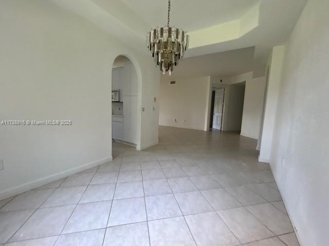7911 W Exeter Blvd W Unit A101, Tamarac, FL 33321 - empty room featuring arched walkways, a chandelier, and light tile patterned floors