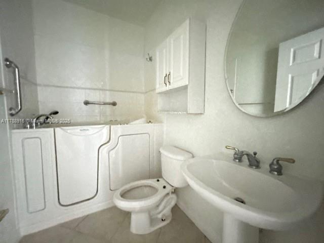 7911 W Exeter Blvd W Unit A101, Tamarac, FL 33321 - bathroom featuring a sink, toilet, tile patterned flooring, and a tub