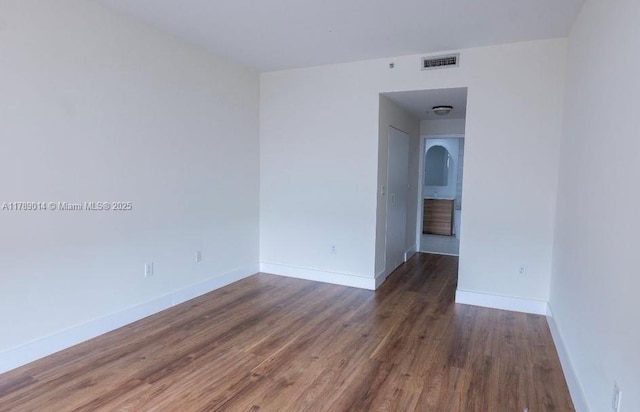 spare room featuring wood finished floors, visible vents, and baseboards