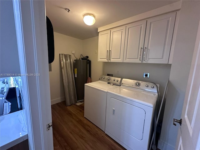 clothes washing area with dark wood finished floors, washing machine and dryer, baseboards, water heater, and cabinet space