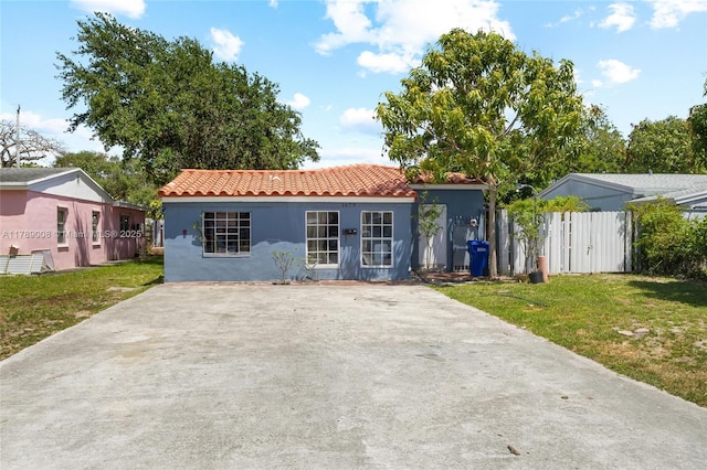 1679 NE 181st St, North Miami Beach, FL 33162 - view of front of property featuring stucco siding, a front lawn, fence, and a tiled roof