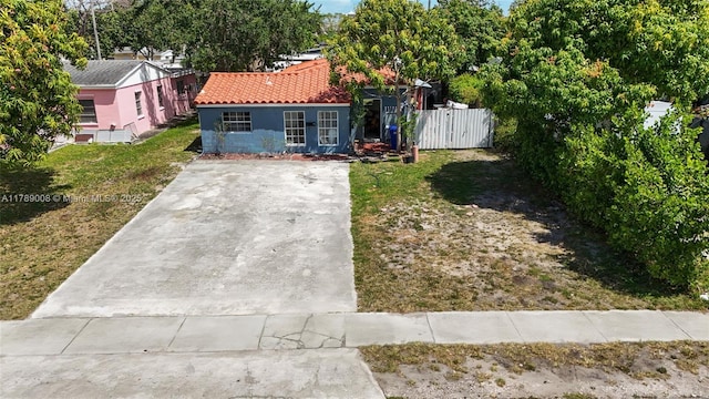 1679 NE 181st St, North Miami Beach, FL 33162 - view of front facade with a gate, fence, concrete driveway, a tile roof, and a front yard