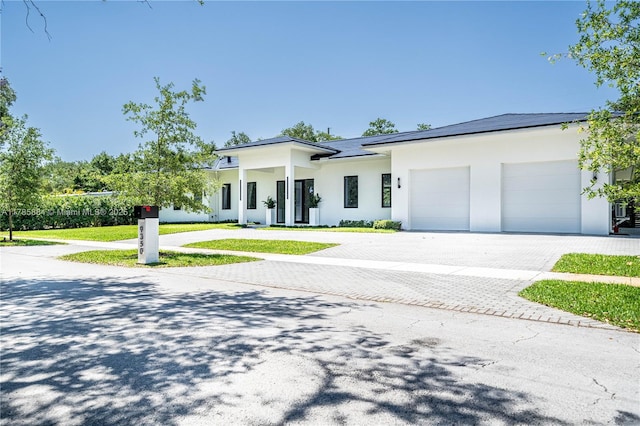 view of front of property featuring stucco siding, an attached garage, and decorative driveway