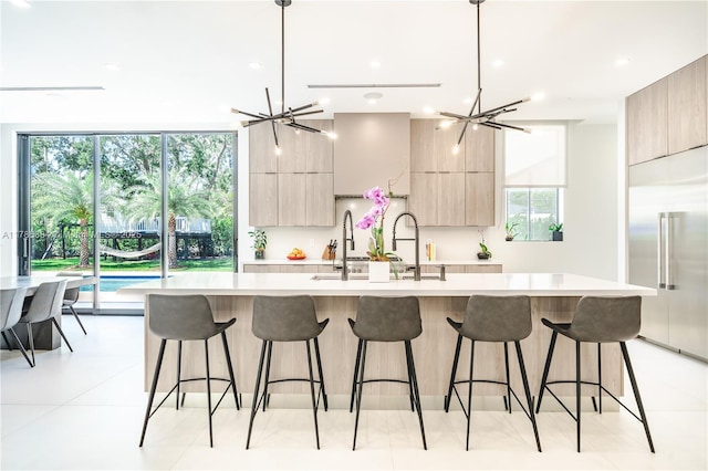 kitchen with modern cabinets, light countertops, light brown cabinetry, and a large island with sink
