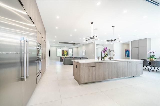 kitchen featuring stainless steel appliances, a large island, light countertops, modern cabinets, and open floor plan