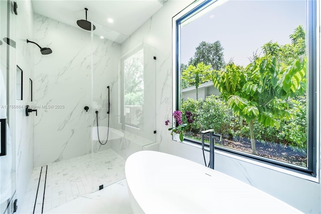 bathroom featuring a freestanding tub, plenty of natural light, and a marble finish shower